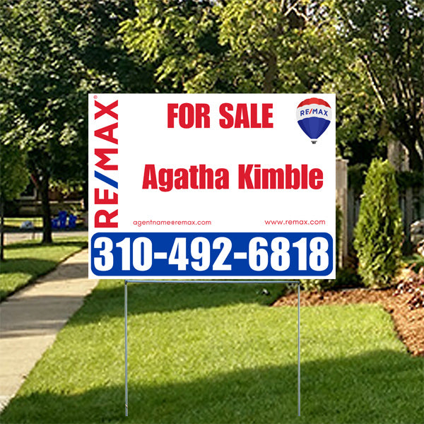 Real estate for sale sign by RE/MAX with agent Agatha Kimble's contact number 310-492-6818 on a grassy residential lawn.