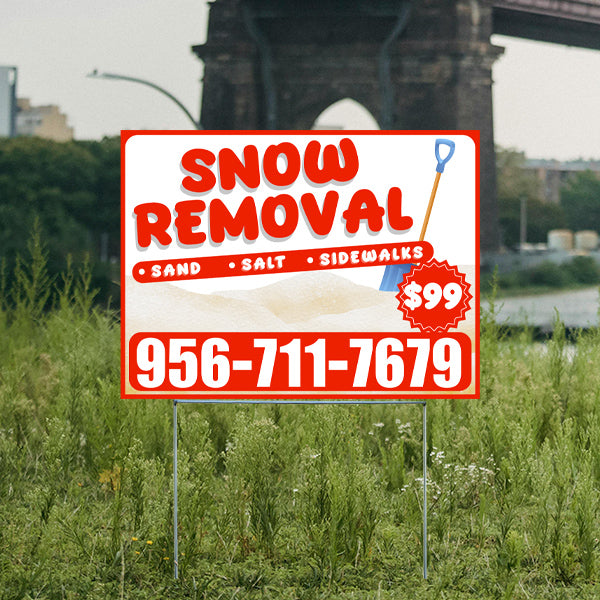 Outdoor advertisement sign for snow removal services featuring a shovel icon, phone number 956-711-7679, and promotional price of $99, displayed on a grassy background with an archway in the distance.