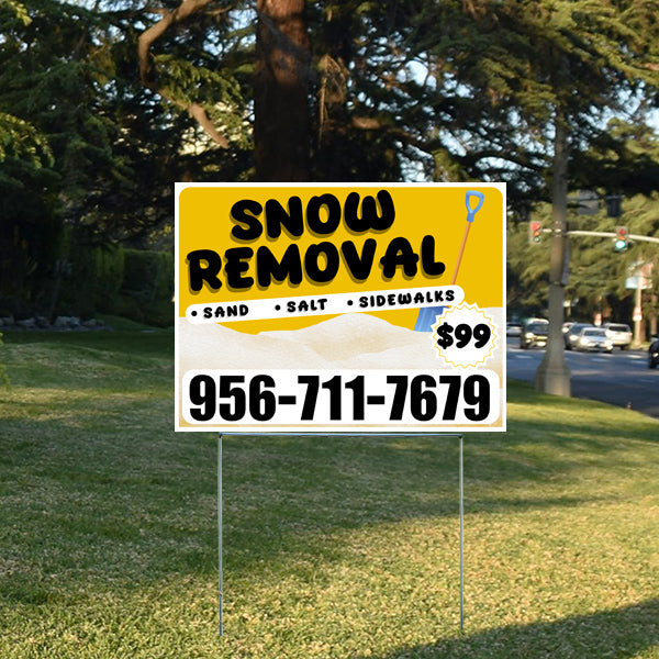 Snow removal service yard sign with contact number 956-711-7679, offering sand, salt, and sidewalk services for $99, placed on a lawn with trees and a street in the background.