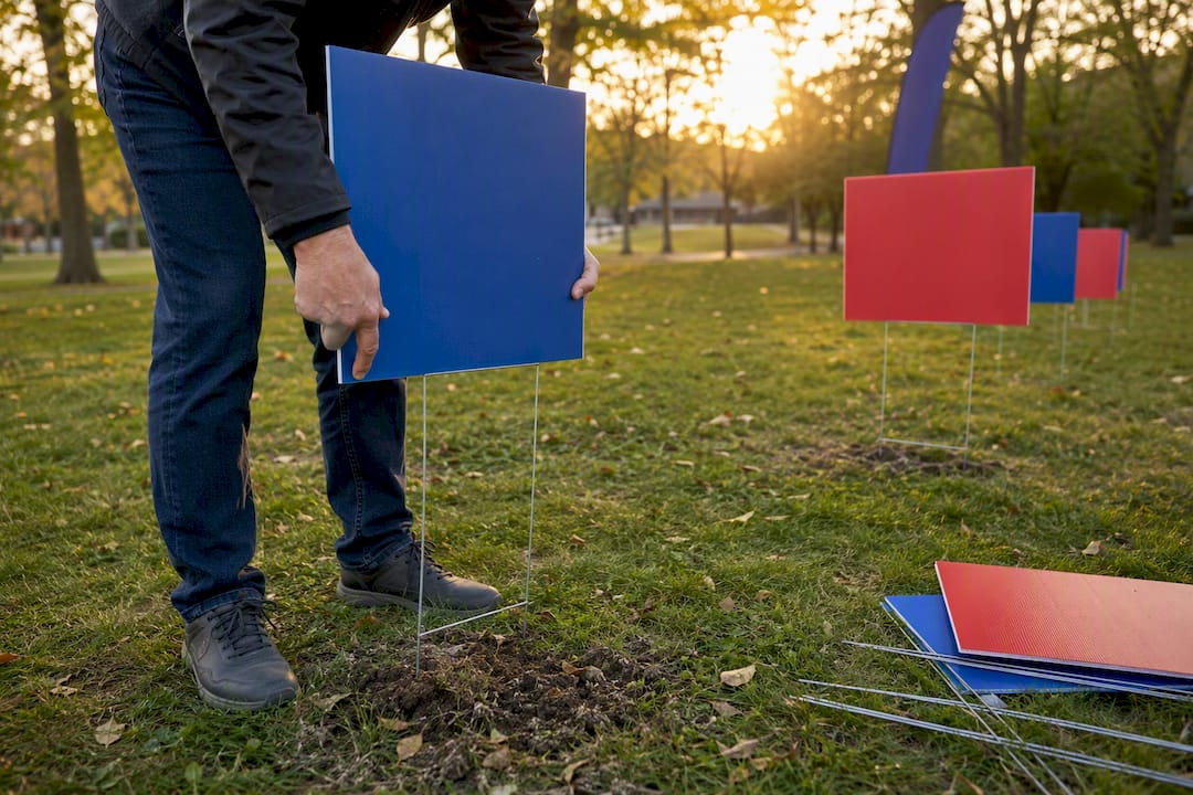 Hands installing outdoor sponsor recognition yard signs