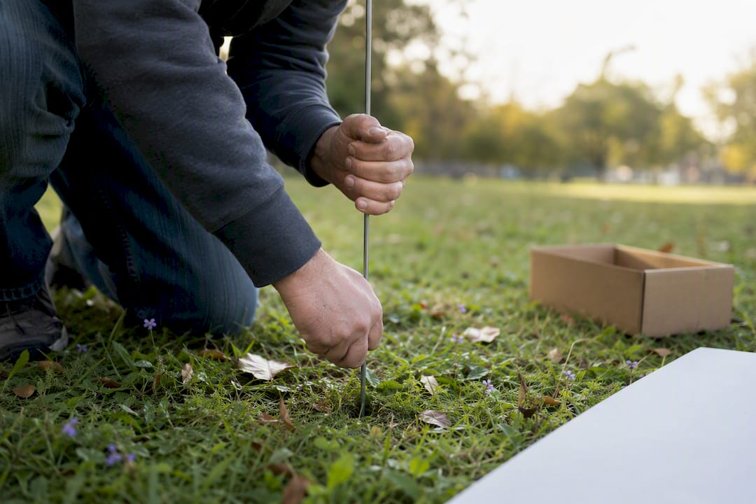 Hands installing campaign yard sign stake in lawn