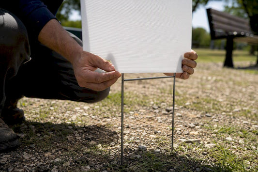 Hands installing political yard sign outdoors