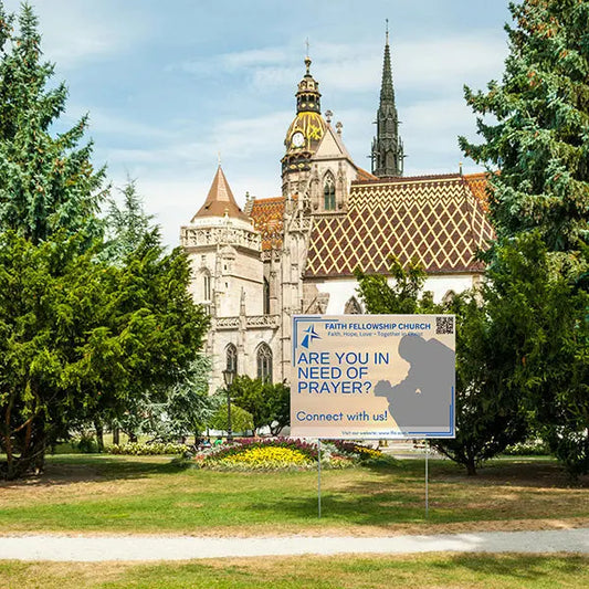 Historic cathedral with prayer sign on church grounds.
