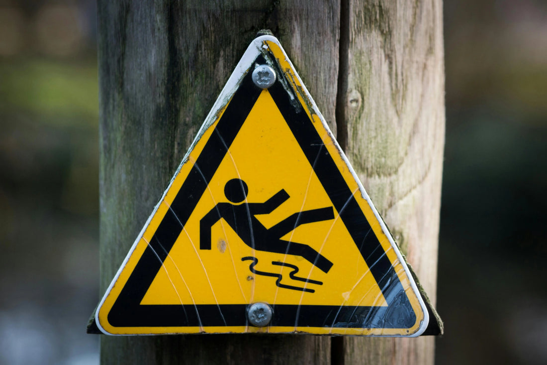 Yellow triangular sign warning of person slipping.
