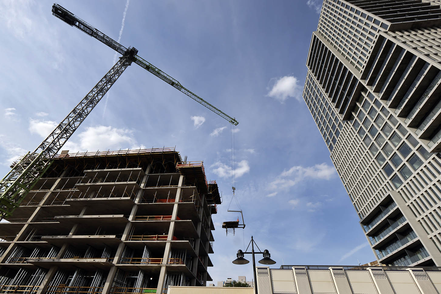 Construction site with a crane and partially built high-rise buildings against a blue sky.