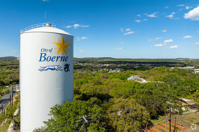 White water tower with 'City of Boerne' branding against a blue sky and green landscape.