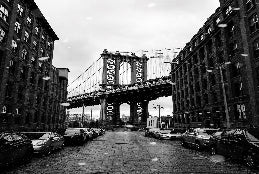 City street with a bridge in the background during snowfall