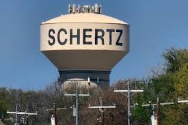 Water tower with 'SCHERTZ' branding against a clear blue sky.