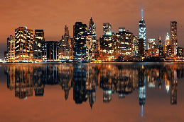 City skyline at night with illuminated buildings reflecting in water