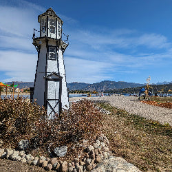 Small lighthouse on a grassy area with mountains in the background