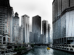 Cityscape with tall buildings and a river, featuring a yellow taxi.
