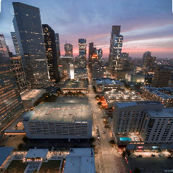Cityscape at dusk with illuminated buildings and streets.