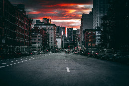 City street with tall buildings and a dramatic sky during sunset.