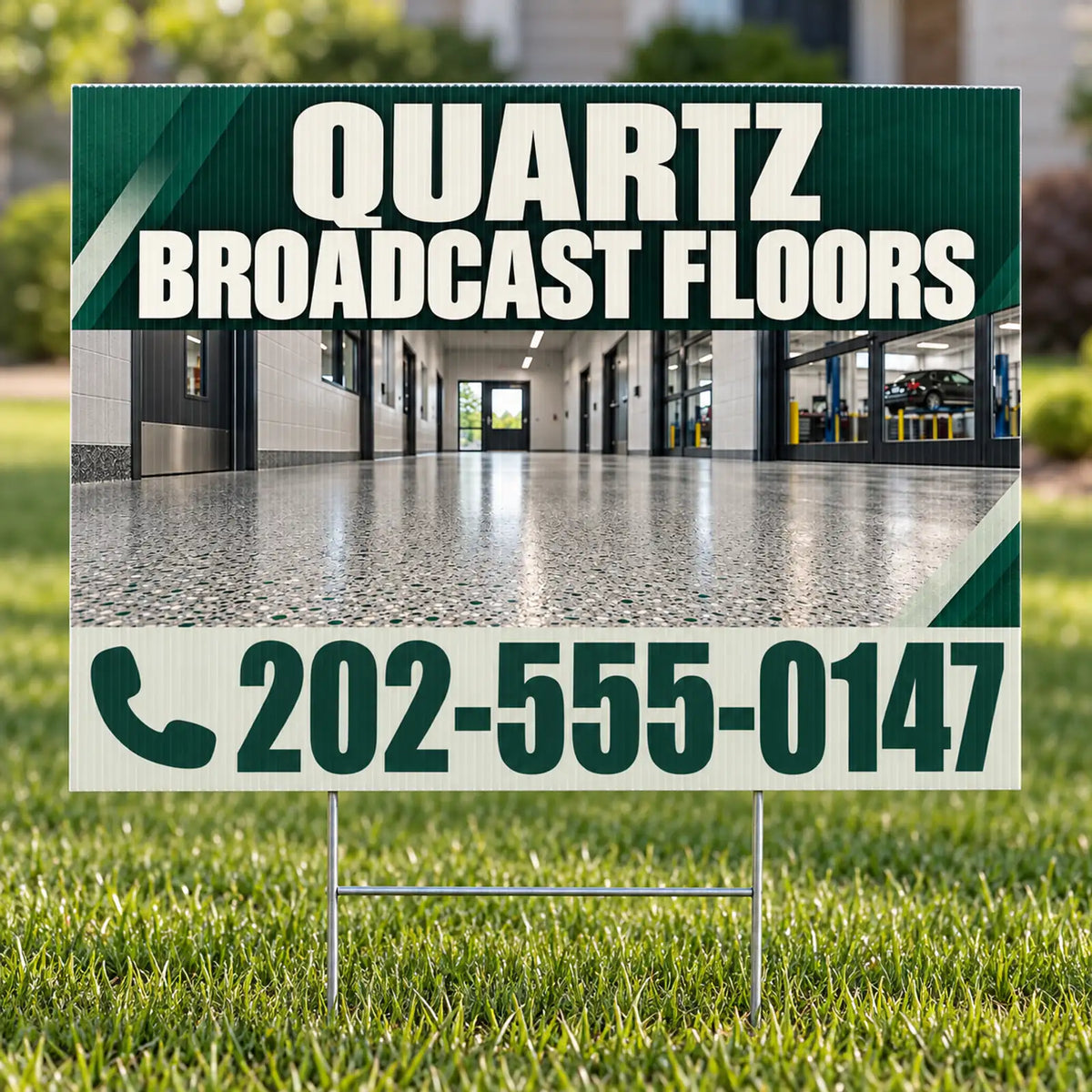A yard sign on metal stakes displayed in a grassy lawn. The sign features a dark green and white design with the text 'QUARTZ BROADCAST FLOORS' and a phone number, with a photo of a polished concrete hallway in the center.
