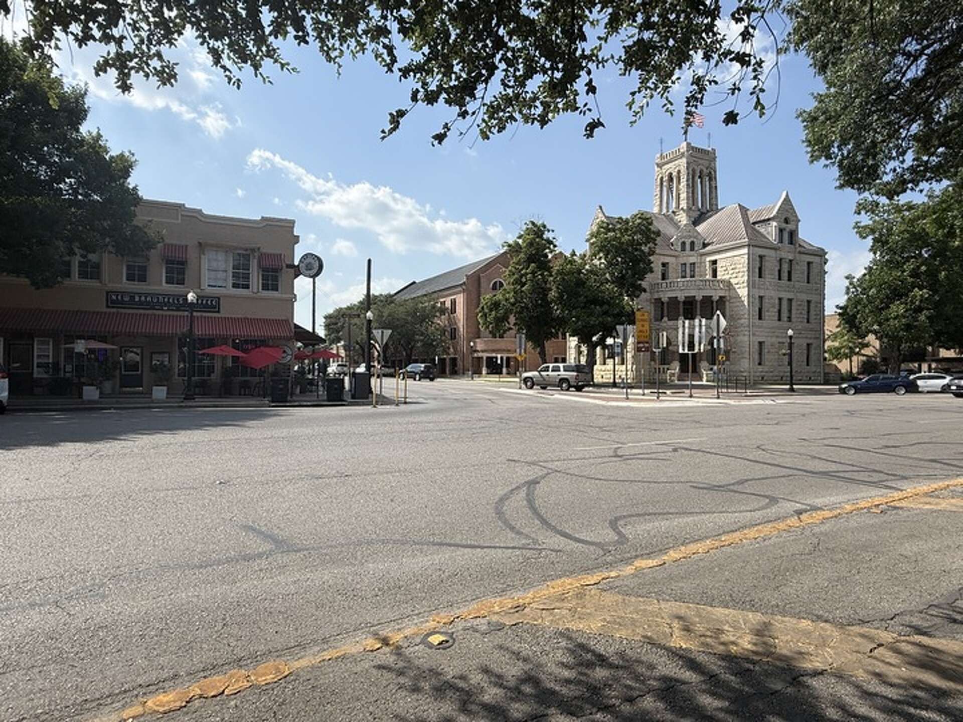 Street scene with a large building and trees on a sunny day