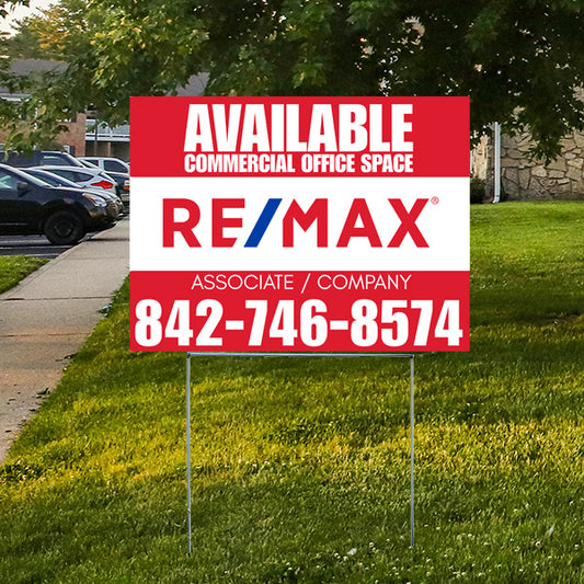 Real estate sign for available commercial office space, RE/MAX logo, contact number 842-746-8574, displayed on grass with trees and parked cars in the background.