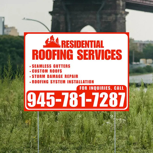 Residential roofing services sign with contact information in a grassy area.