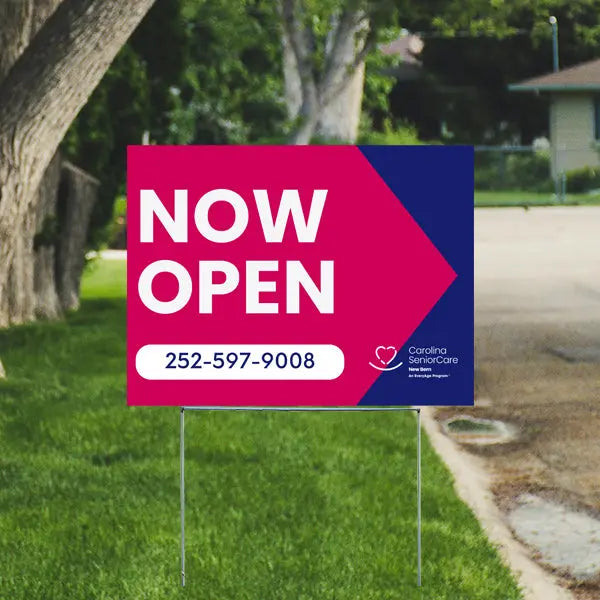 Now open sign for Carolina Senior Care with contact number 252-597-9008 on a lawn.