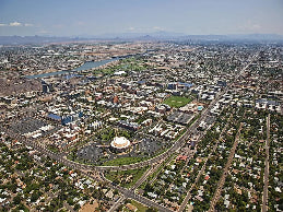 Aerial view of a city with a large stadium in the center, surrounded by roads and buildings.