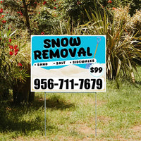 Snow removal service yard sign with contact number 956-711-7679, offering sand, salt, and sidewalk clearing for $99, displayed in a garden setting.
