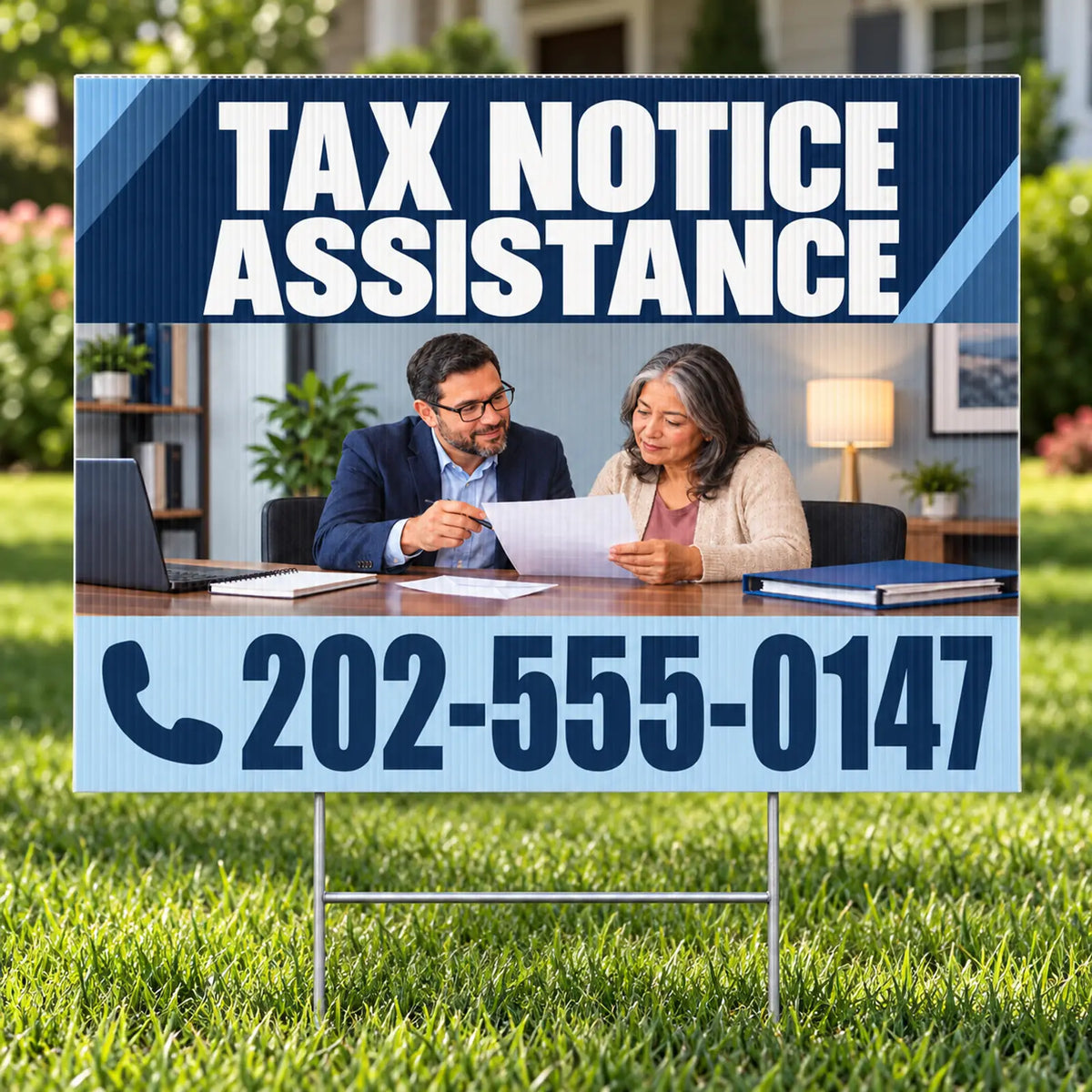 A yard sign on a metal stake in a grassy lawn, featuring a printed design with the text 'TAX NOTICE ASSISTANCE' and a phone number '202-555-0147'. The center of the sign shows a photo of a man and woman sitting at a desk reviewing papers.